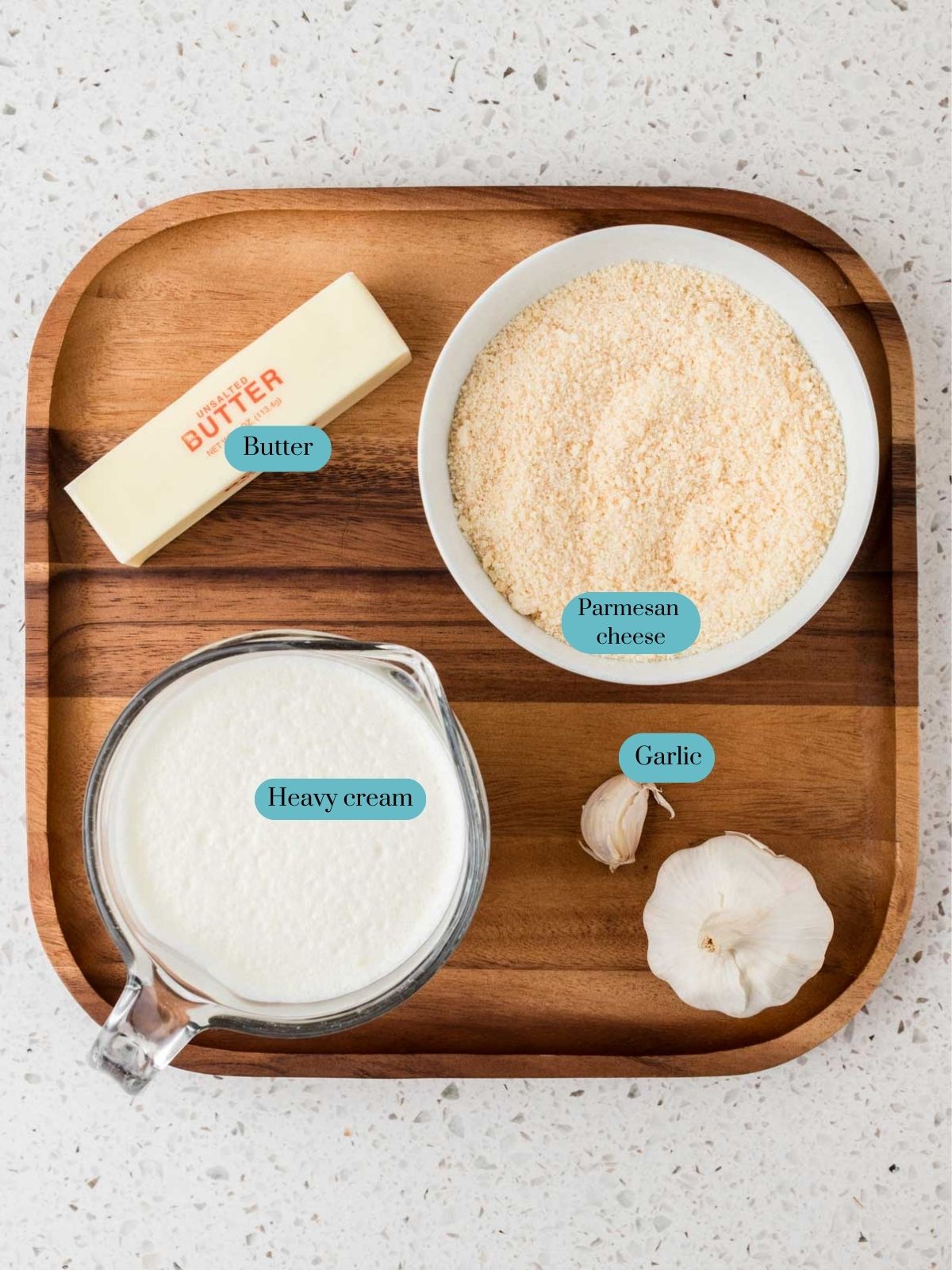 Ingredients arranged on a tray. Ingredients include, butter, parmesan cheese, heavy cream, and garlic.