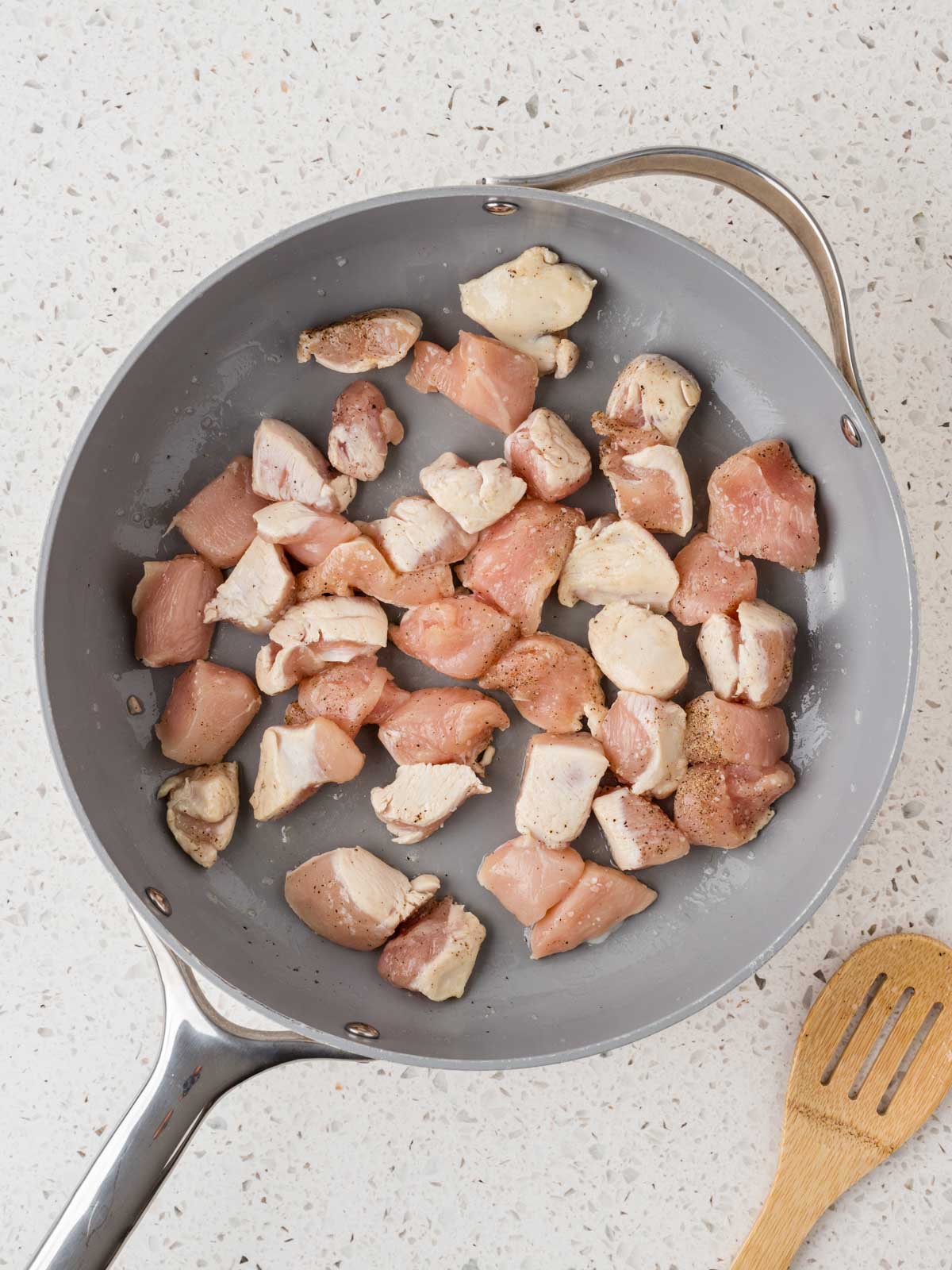 Cubed chicken in a saute pan. 