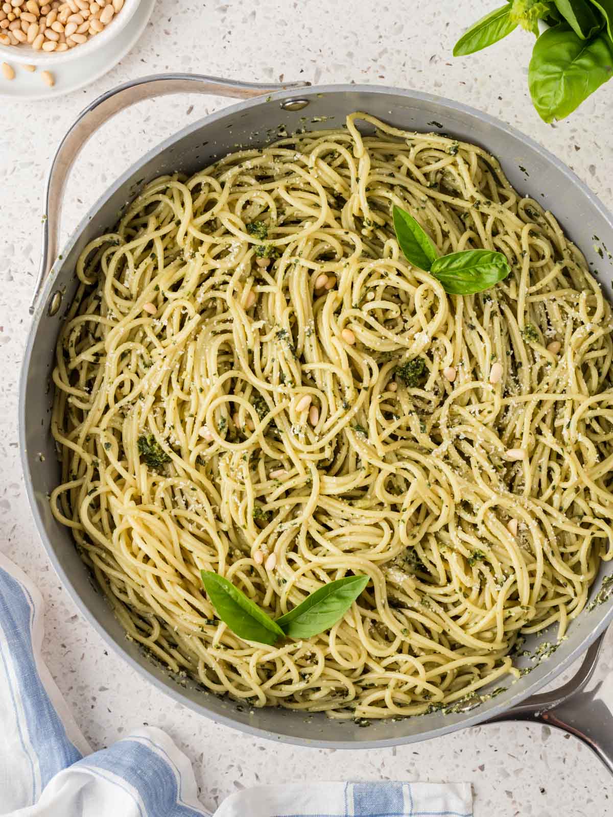 Basil pesto pasta in a large pan that is garnished with fresh basil leaves.