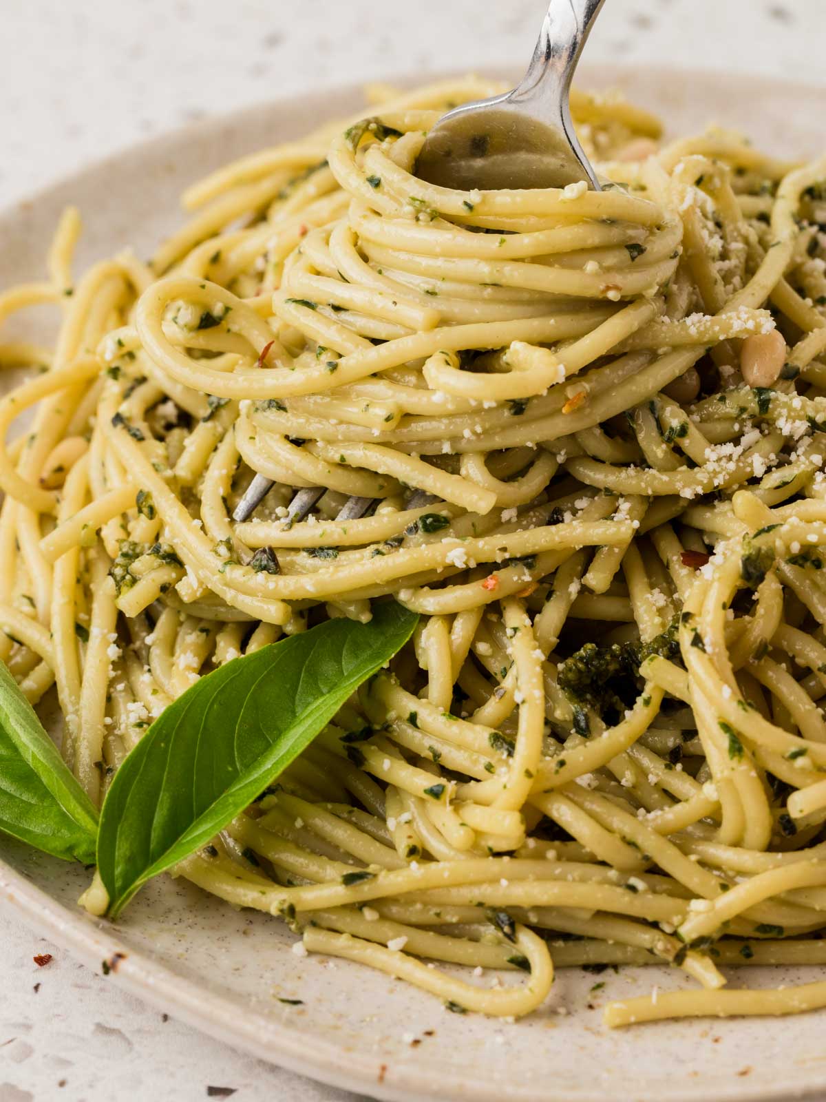 Basil Pesto Pasta on a plate and twirled around a fork, garnished with fresh basil.