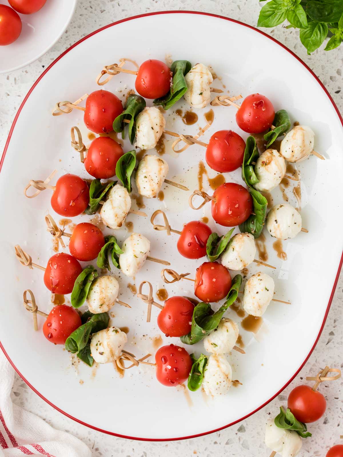 Caprese skewers arranged on a platter drizzled with olive oil and balsamic glaze. 