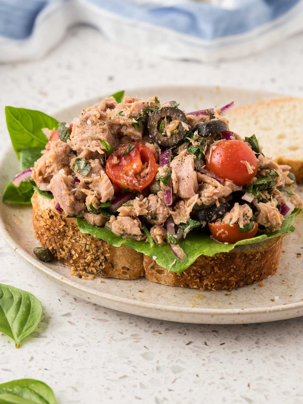 A single piece of bread topped with a piece of romaine lettuce and a serving of Italian Tuna Salad. 