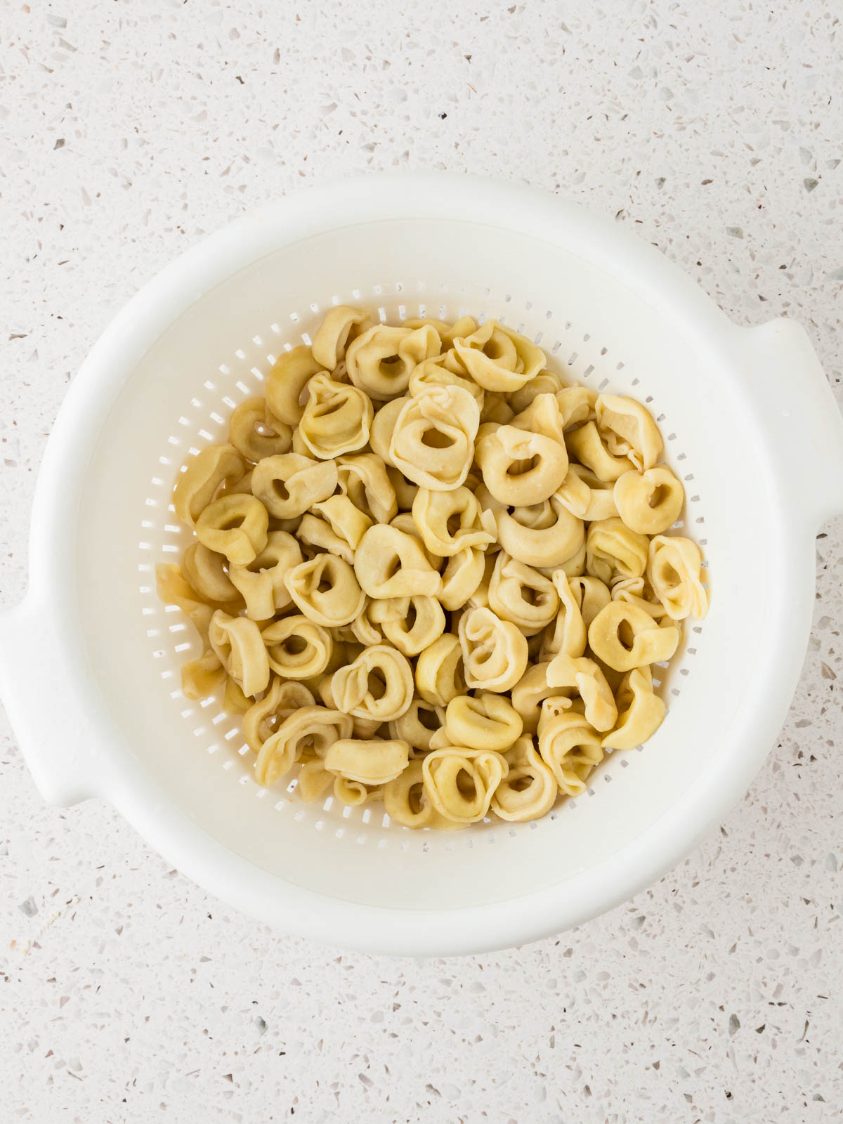 Cooked and drained tortellini in a colander.