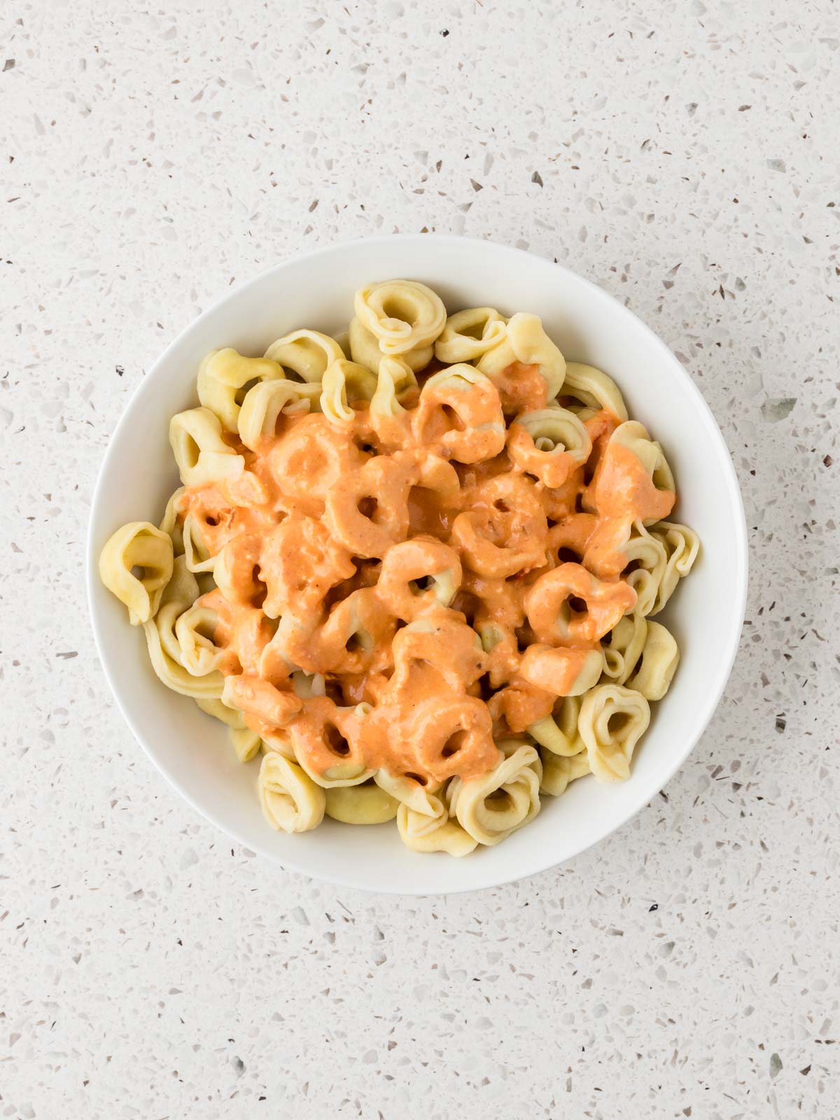 Sauce poured over tortellini in a serving bowl.