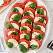 Caprese salad on a white platter with a drizzle of balsamic glaze.