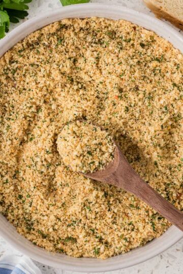 Homemade Italian breadcrumbs in a serving bowl with a wooden spoon.