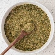Homemade Italian seasoning in a serving bowl with a wooden spoon.