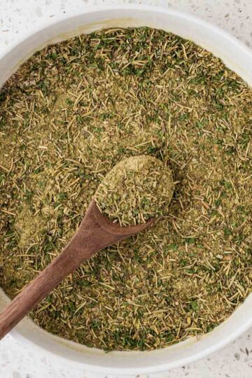Homemade Italian seasoning in a serving bowl with a wooden spoon.