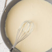 Homemade alfredo sauce in a pan with a whisk.