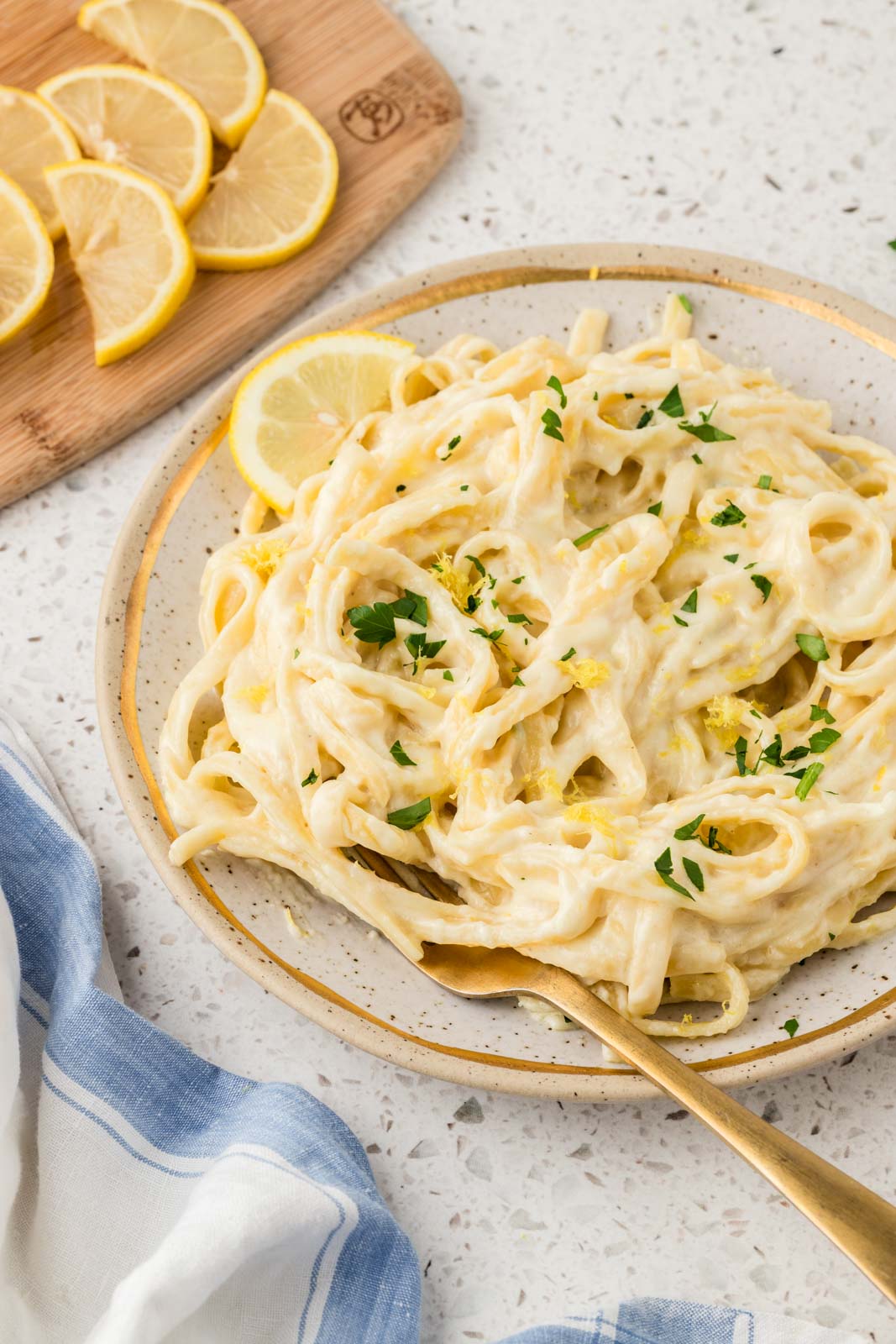 Lemon Fettucine Alfredo garnished with parsley and lemon zest plated with a fork
