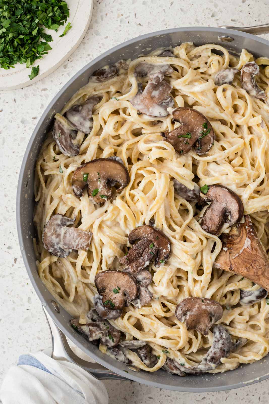 Creamy Mushroom Fettuccine Alfredo in a pan with a wooden spoon. 