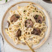 Creamy Mushroom Fettuccine Alfredo plated with a gold fork.