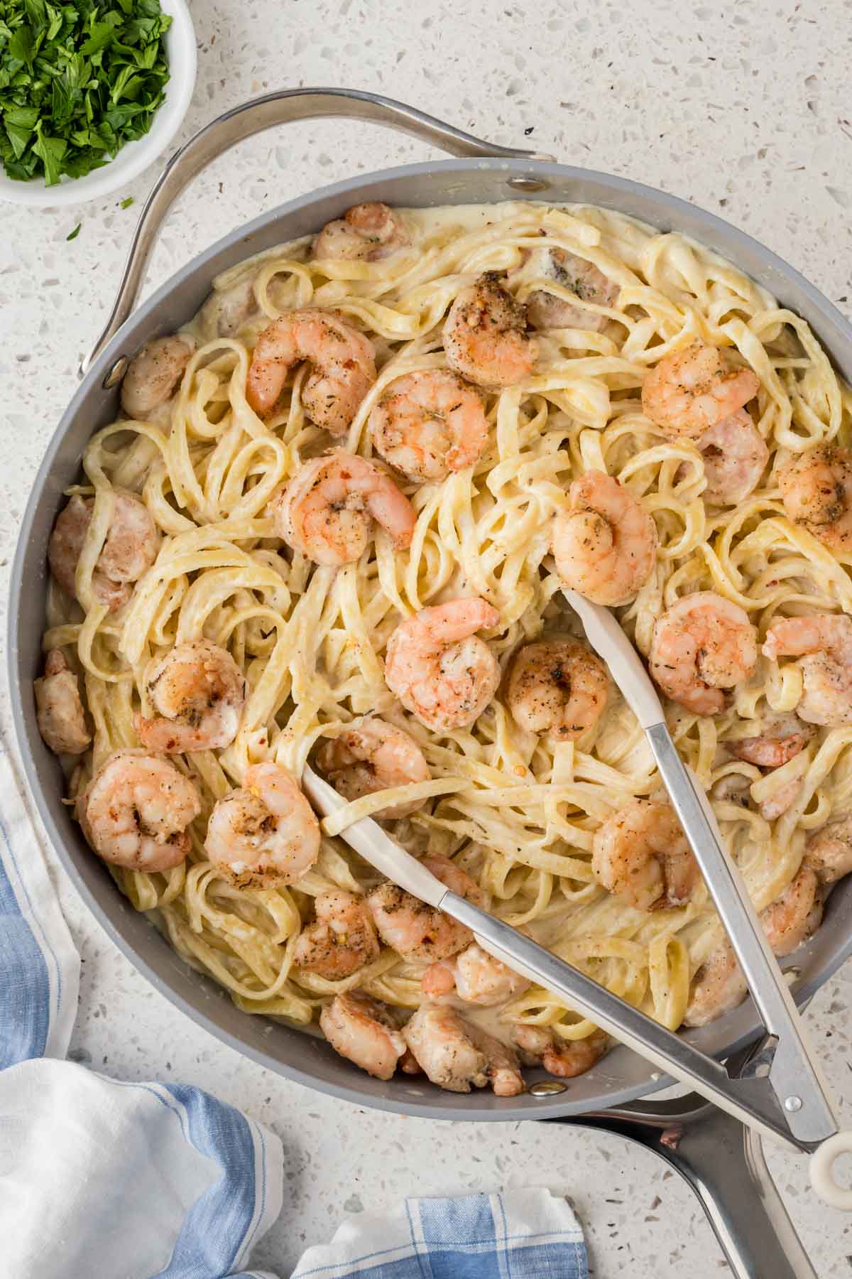 Creamy Shrimp Fettuccine Alfredo in a pan with tongs for serving.