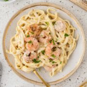 Shrimp fettuccine alfredo plated with a fork and garnished with parsley.
