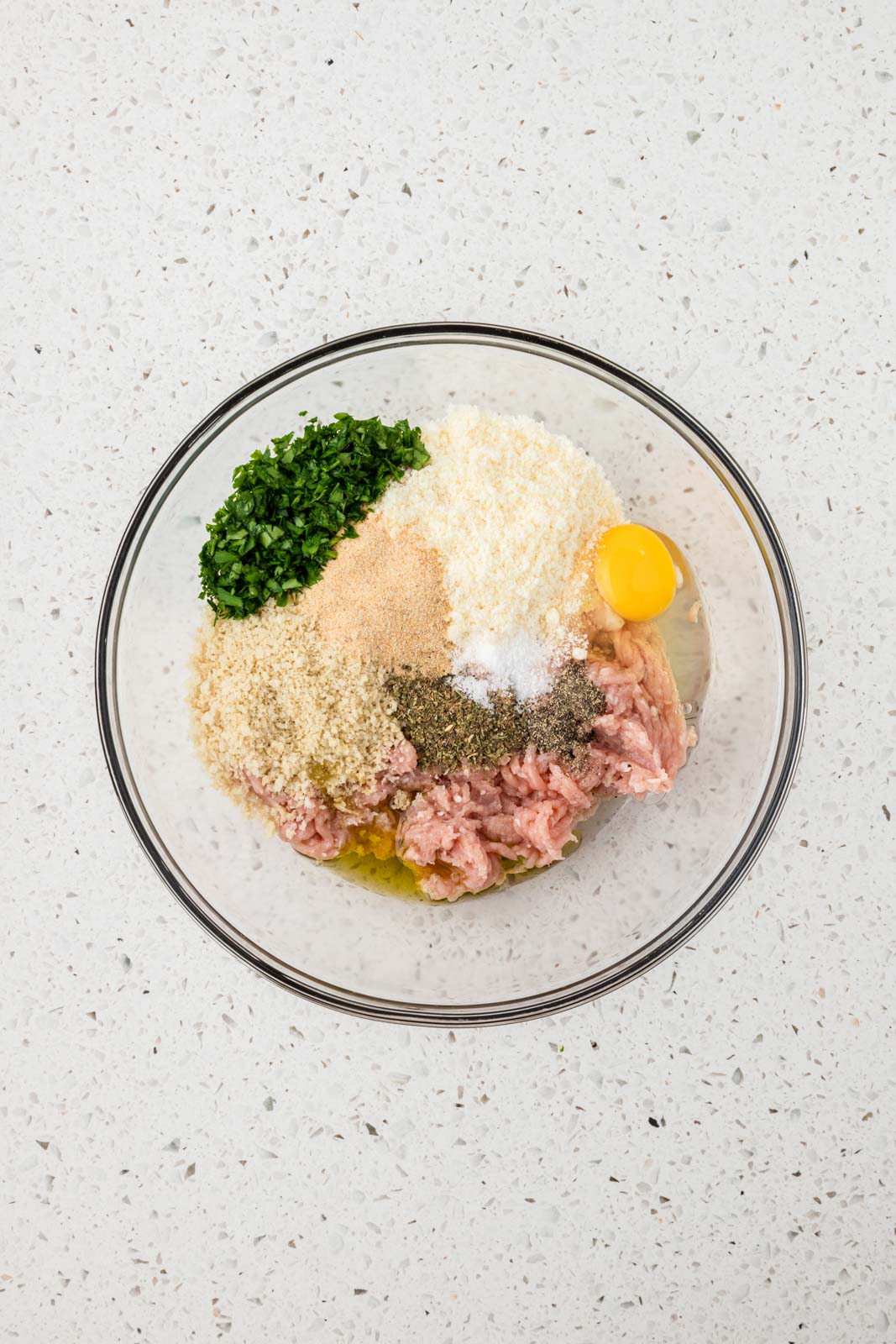 All ingredients for Italian chicken meatballs in a mixing bowl.