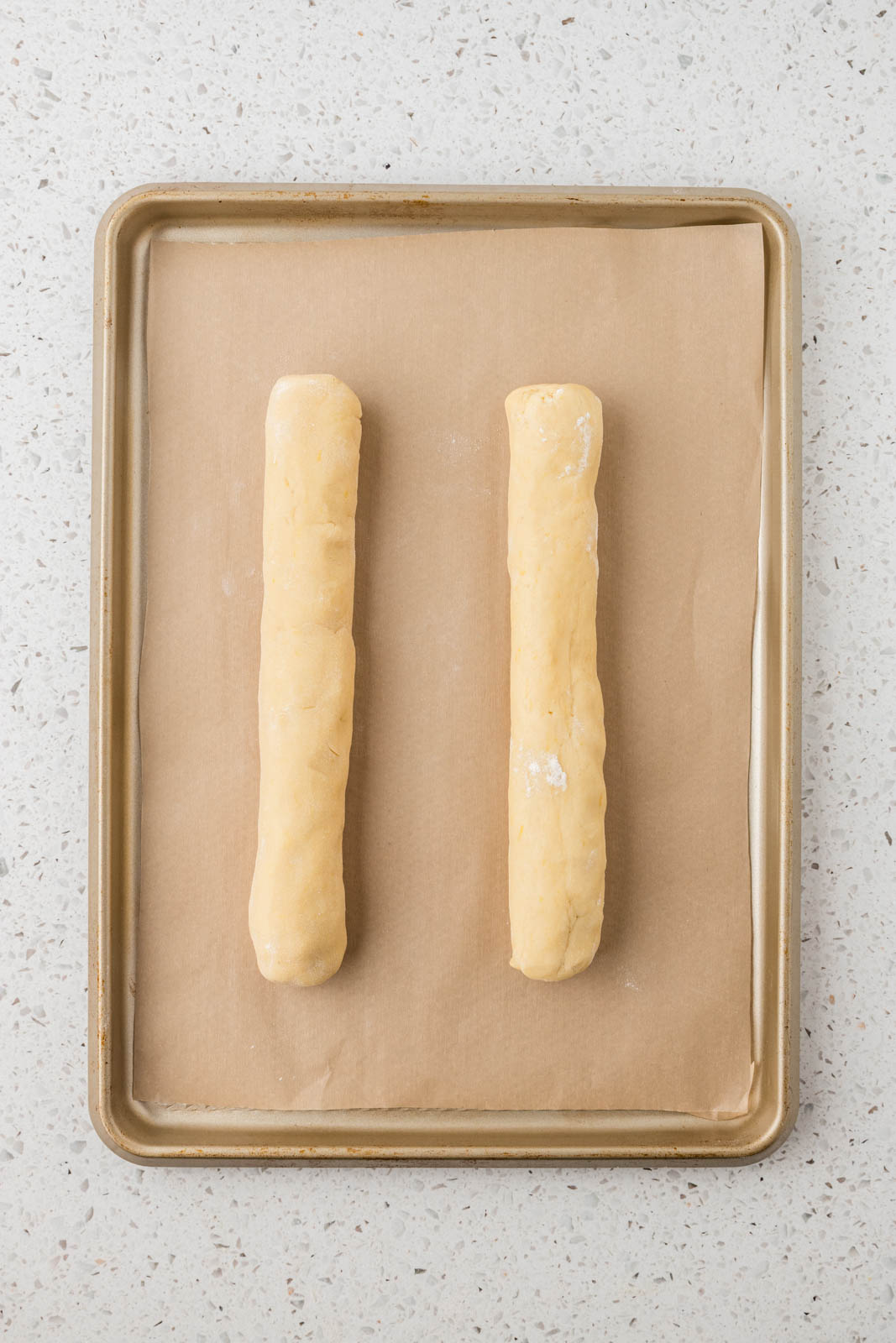 Lemon biscotti dough on baking sheet with parchment paper.