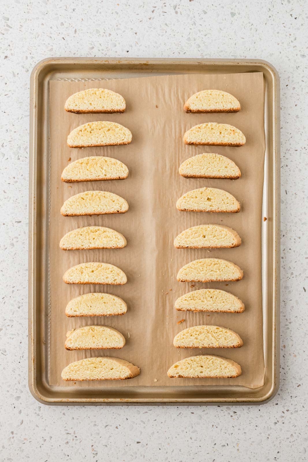 Slice lemon biscotti on a baking sheet.