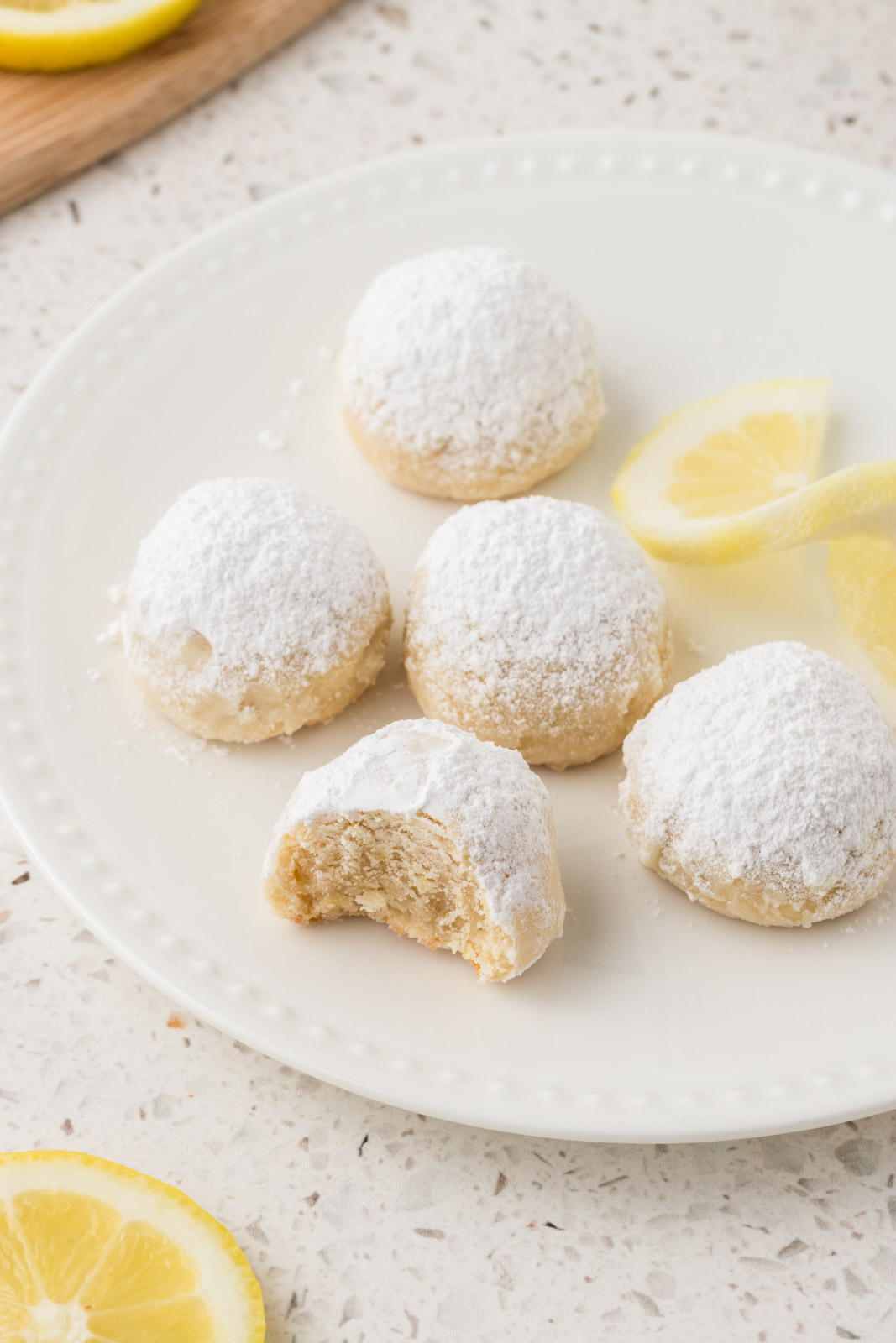 Plate with lemon snowball cookies. One is missing a bite. 