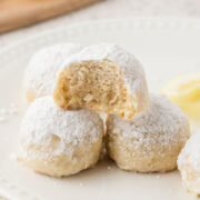 Lemon snowball cookies stacked with a bite out of the top cookie.
