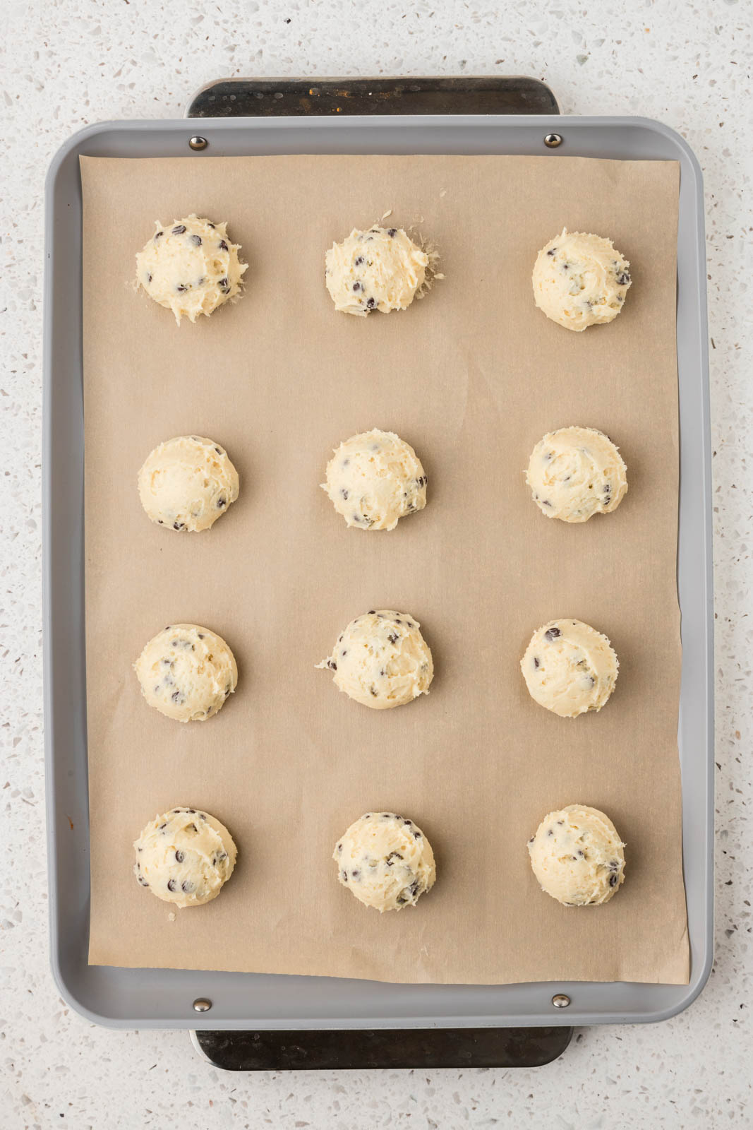 Cannoli cookie dough balls on a cookie sheet.