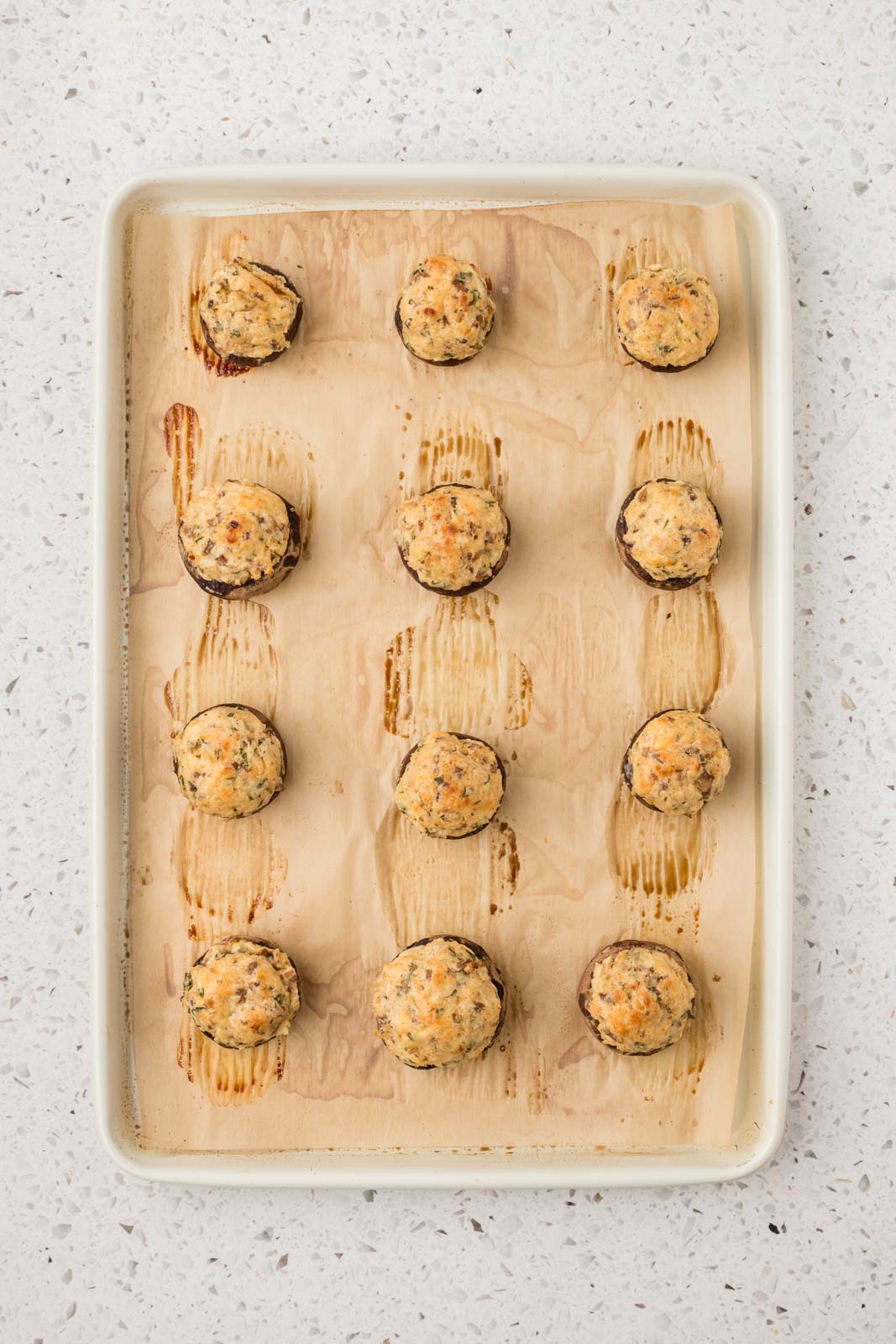 Italian stuffed mushrooms are baked on a cookie sheet.
