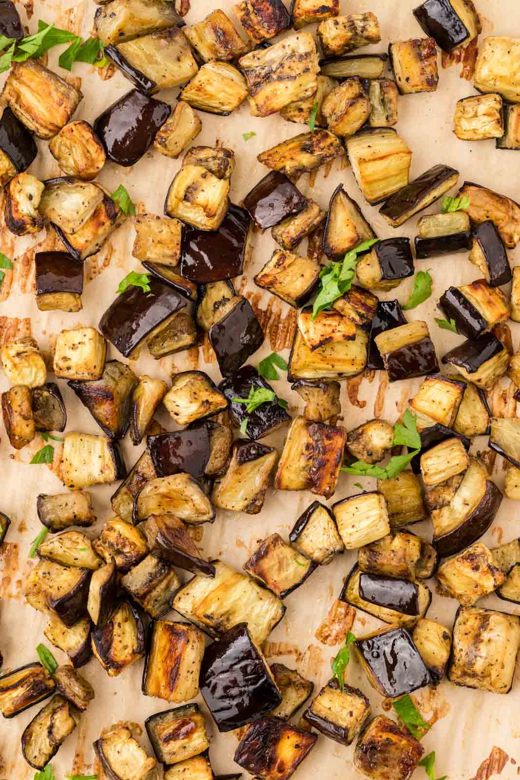 Roasted eggplant on a sheet pan garnished with parsley.