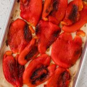 Roasted red peppers on a parchment-lined baking sheet.