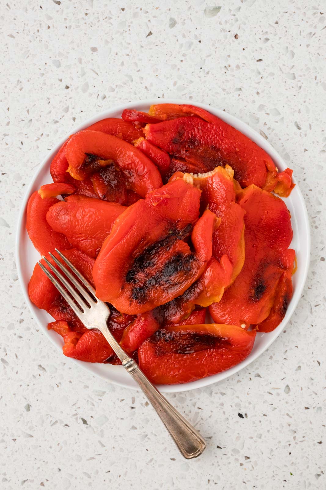 Roasted red peppers on a plate with a fork.