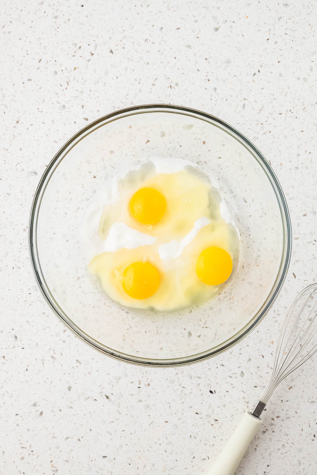 Eggs and sugar in a mixing bowl.