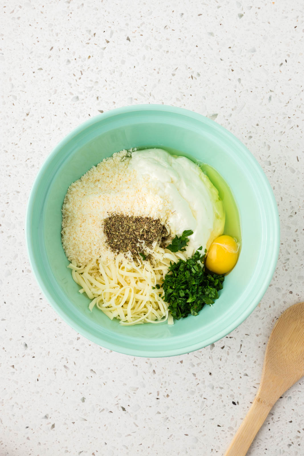 Ricotta, mozzarella, parmesan, egg, parsley and seasonings in a mixing bowl.
