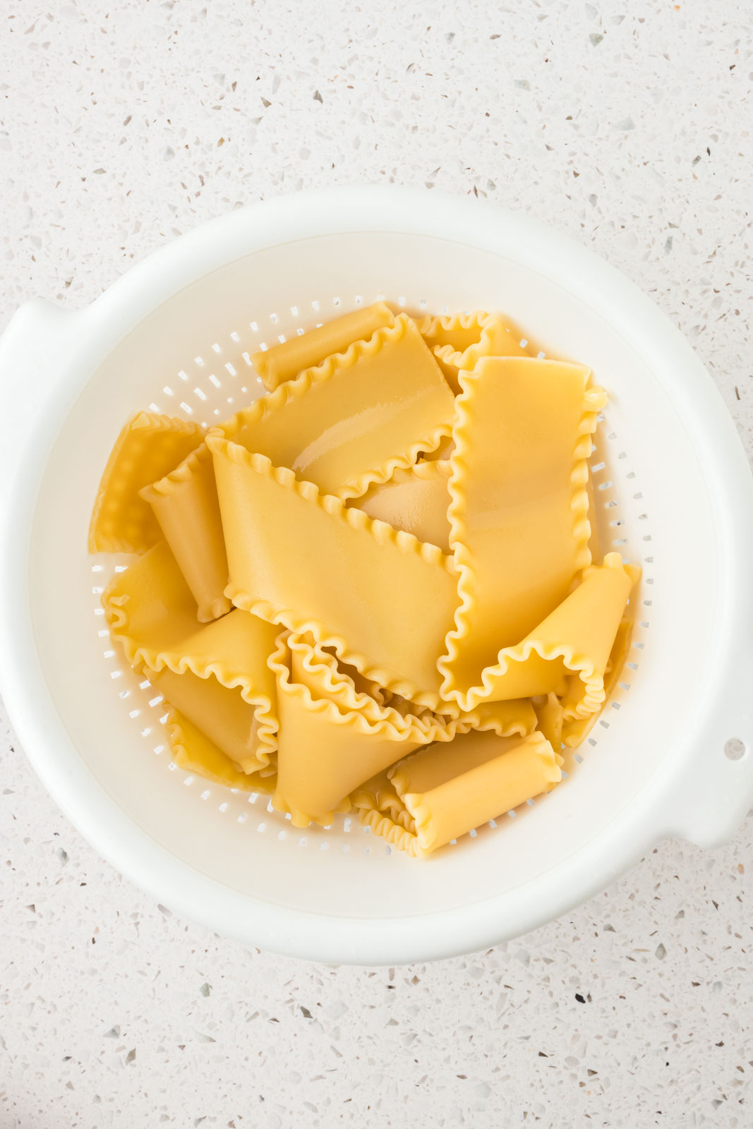 Cooked lasagna noodles in a colander.