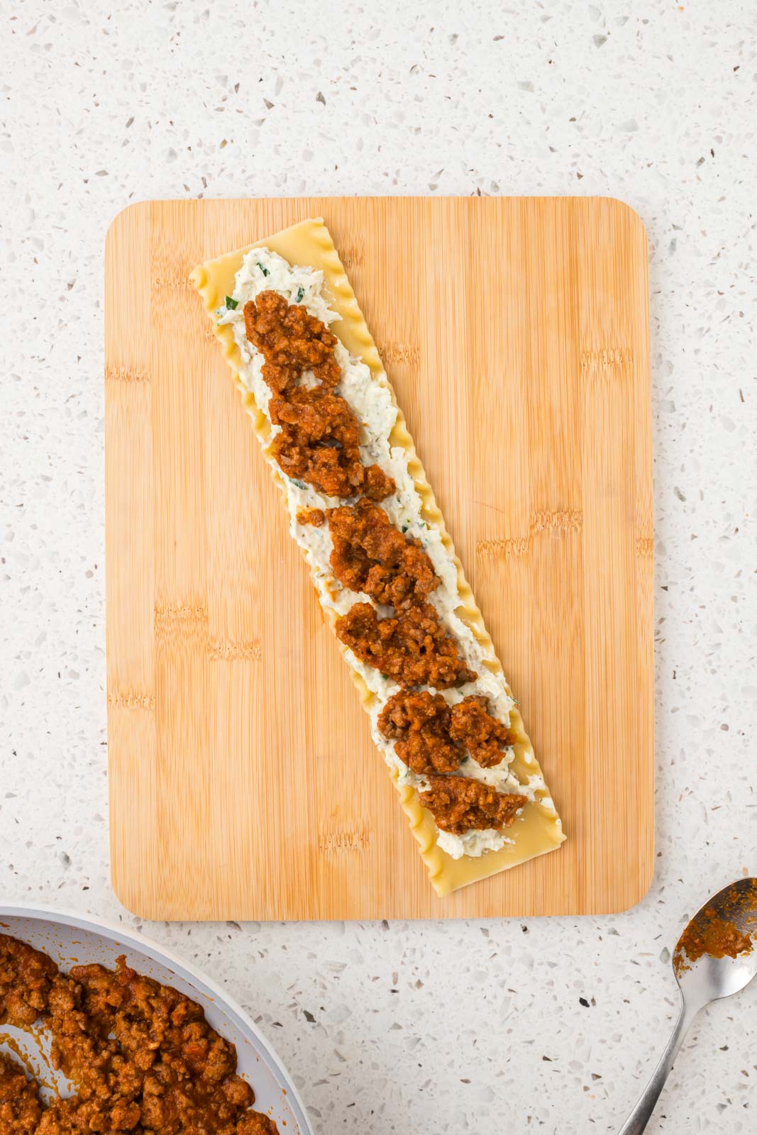 Meat mixture added on top of cheese mixture on the noodle.