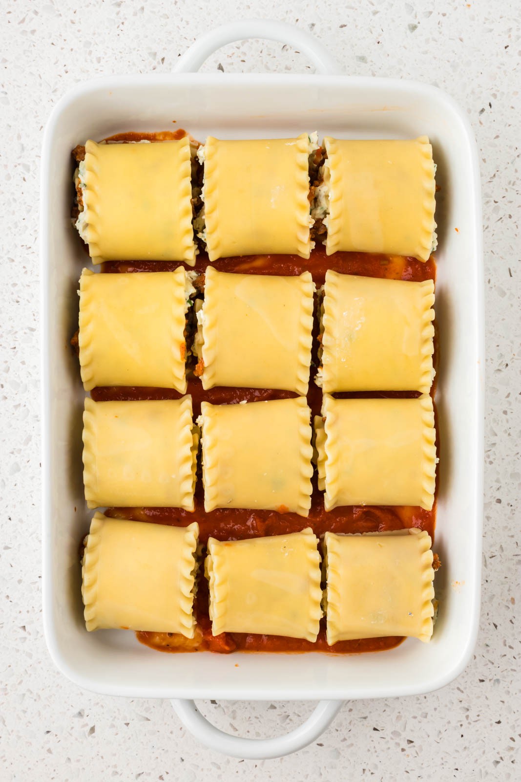 Rollatini seam side down in a baking dish.