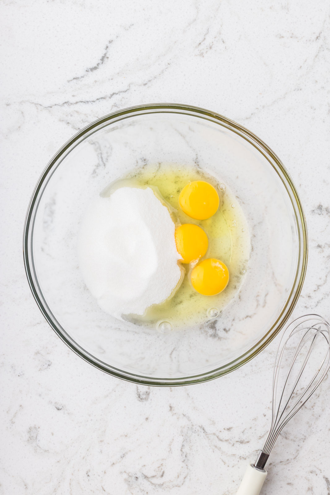 Eggs and granulated sugar in a mixing bowl.