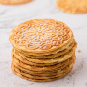 Pizzelle stacked on the counter, sprinkled with powdered sugar.