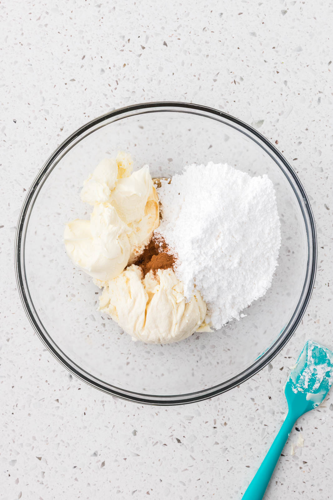 Mascarpone cheese, ricotta cheese, cinnamon and powdered sugar in a mixing bowl.