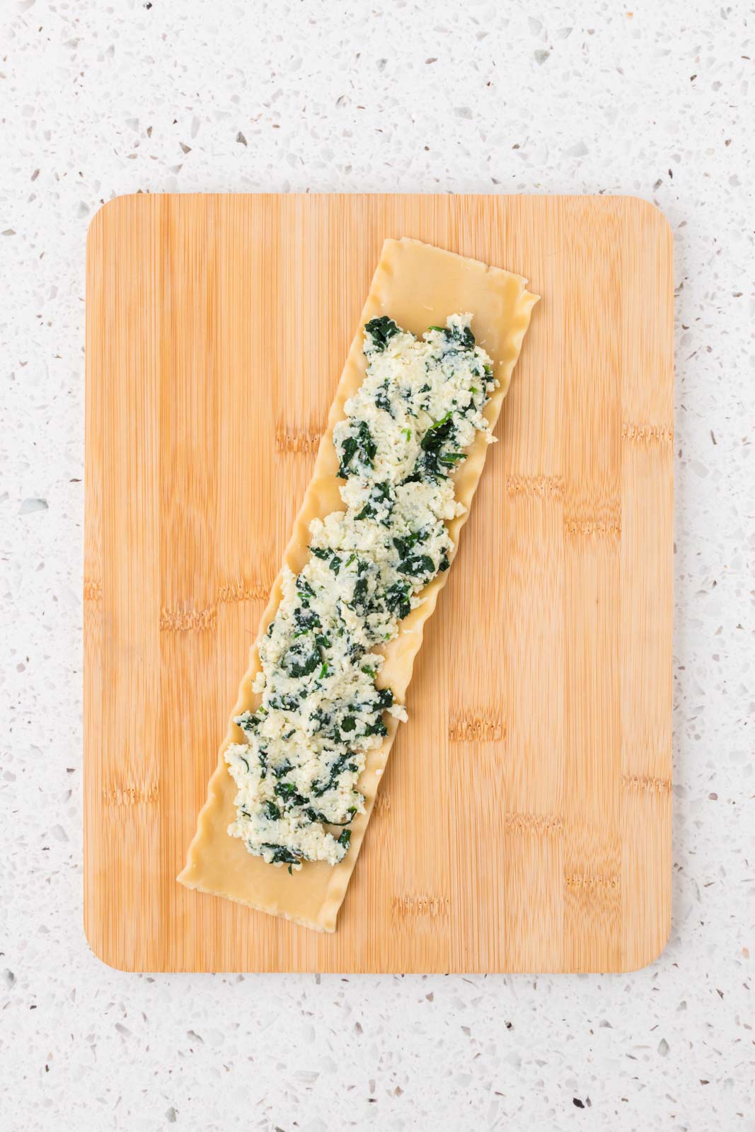 Lasagna noodle with spinach ricotta mixture spread evenly.