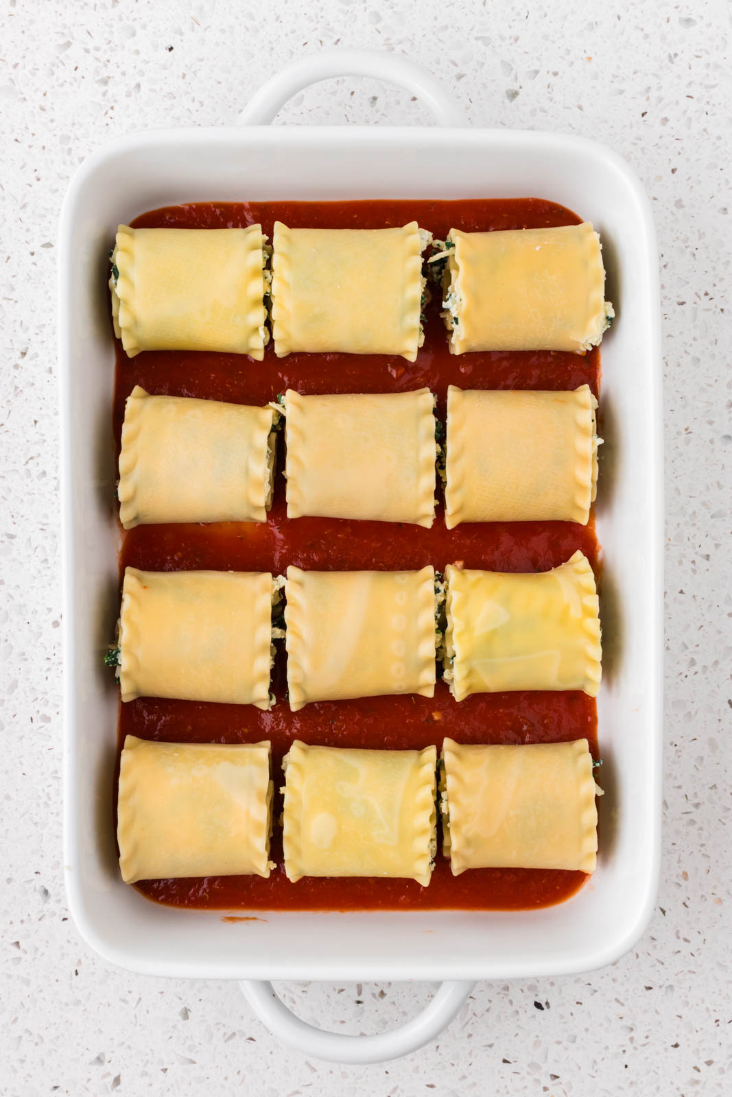 Spinach lasagna roll ups rolled in a baking dish.