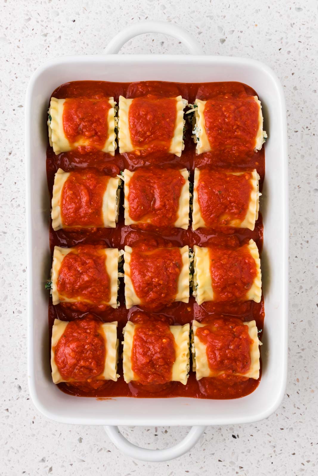Spinach lasagna roll ups topped with marinara sauce.