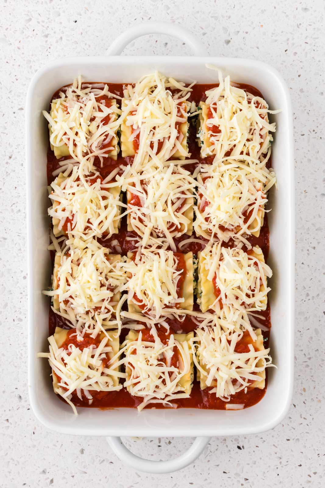 Spinach lasagna roll ups with shredded mozzarella.