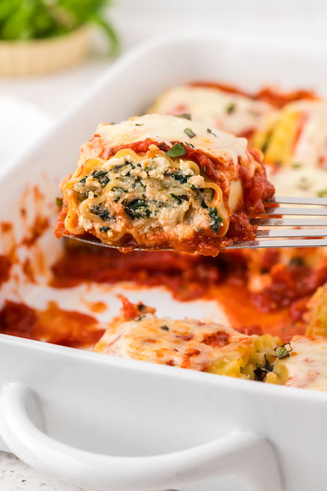 Spinach lasagna roll up on a spatula.