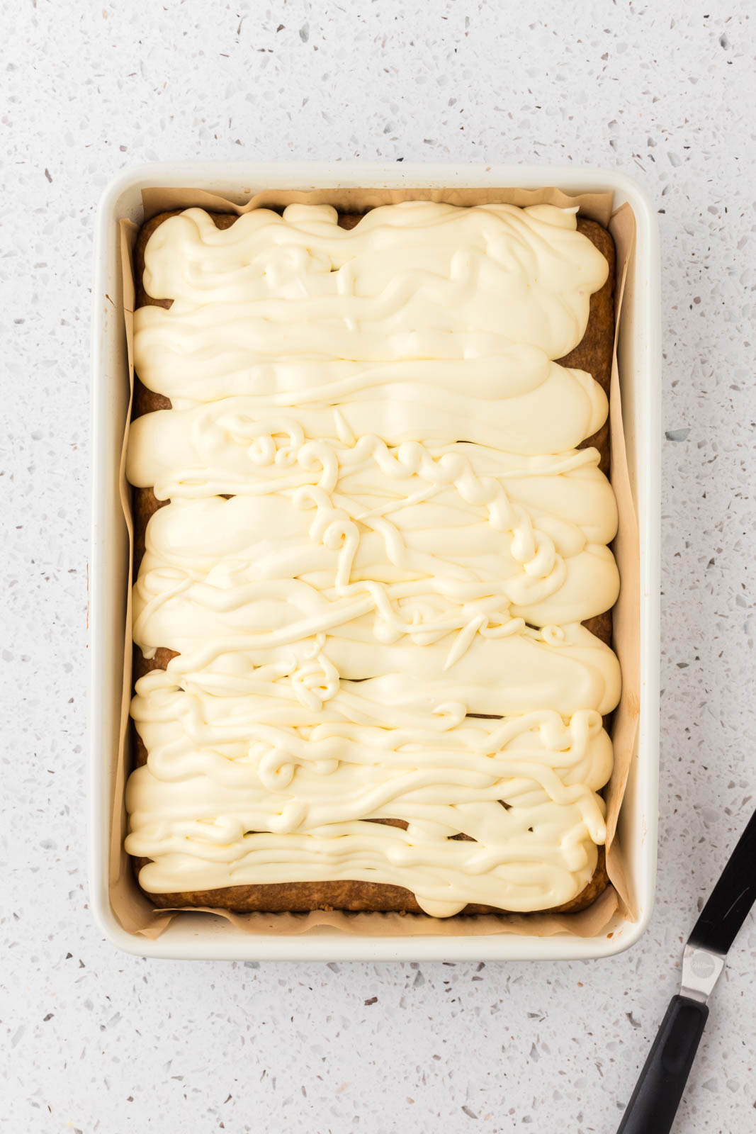 Tiramisu poke cake with filling piped in holes and spread on top of cake.