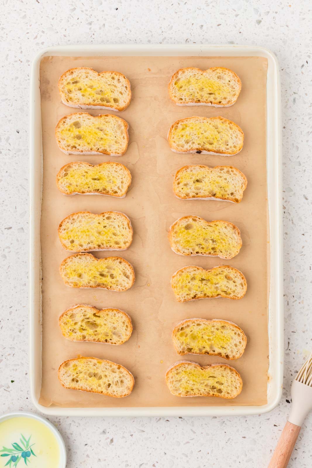 Sliced bread on baking sheet brushed with olive oil.