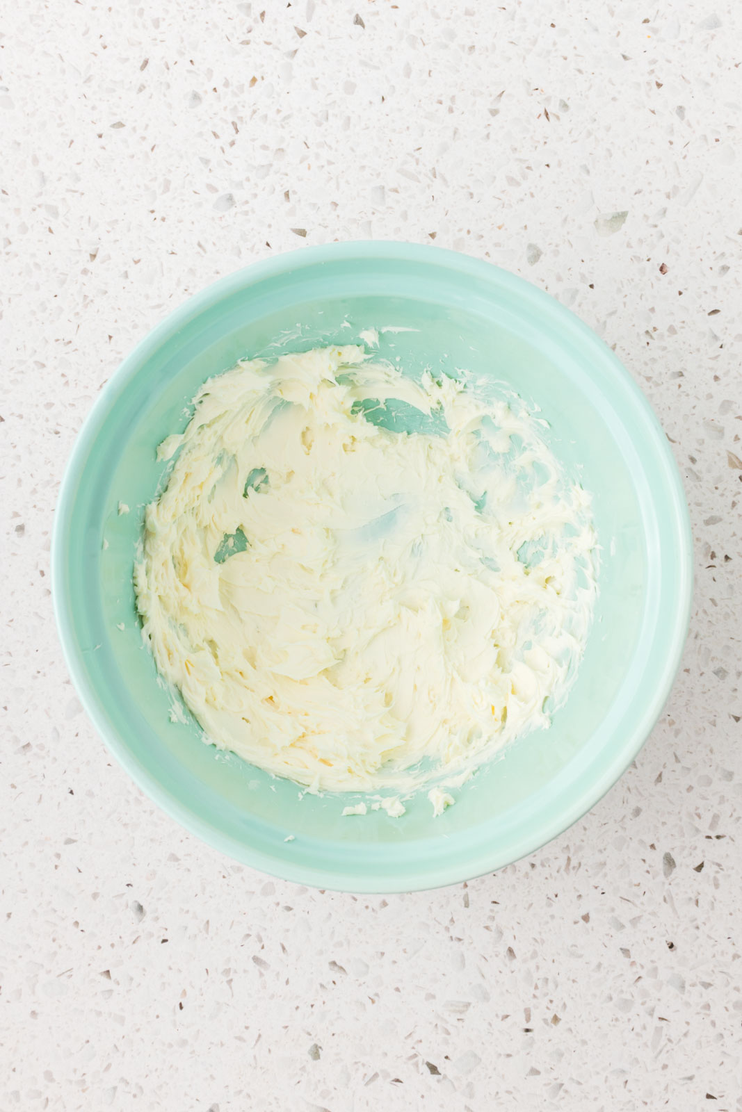 Cream cheese is blended in a mixing bowl.