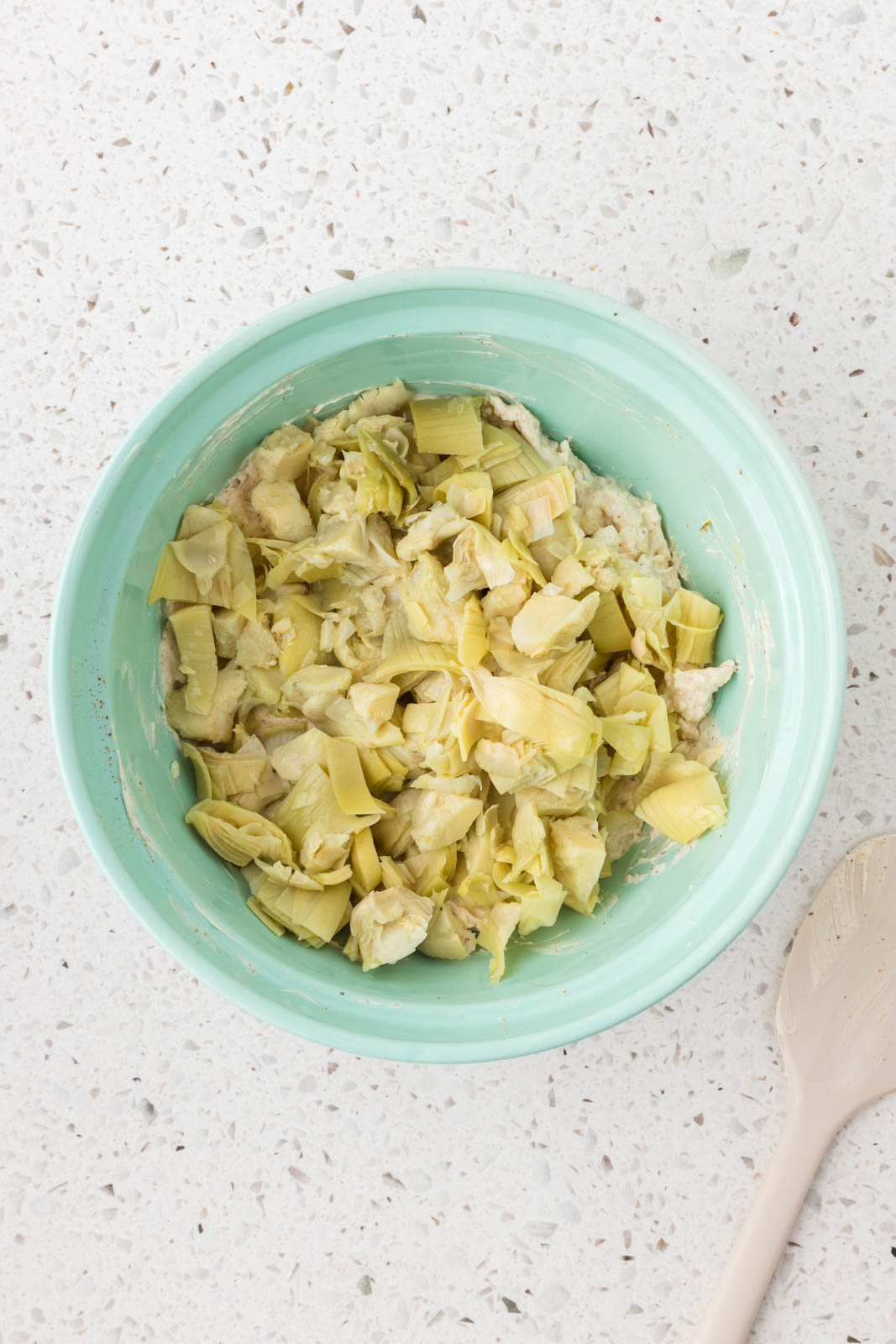 Added chopped artichokes to the mixing bowl.