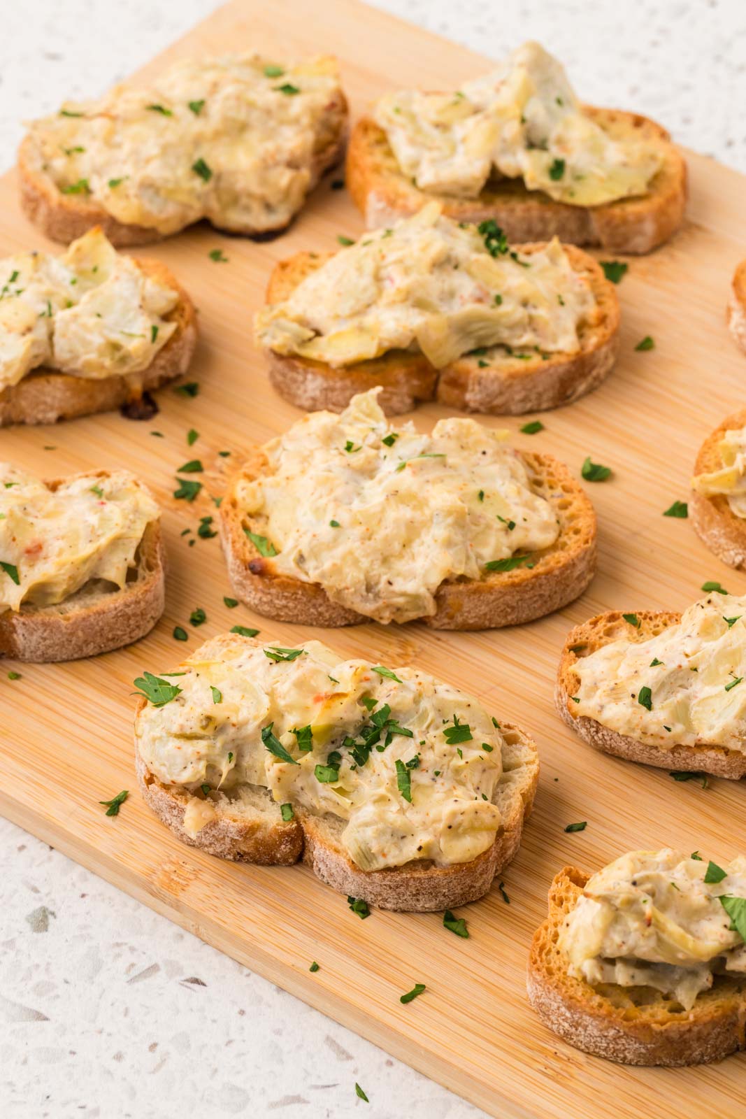 Artichoke bruschetta on a wooden serving board.