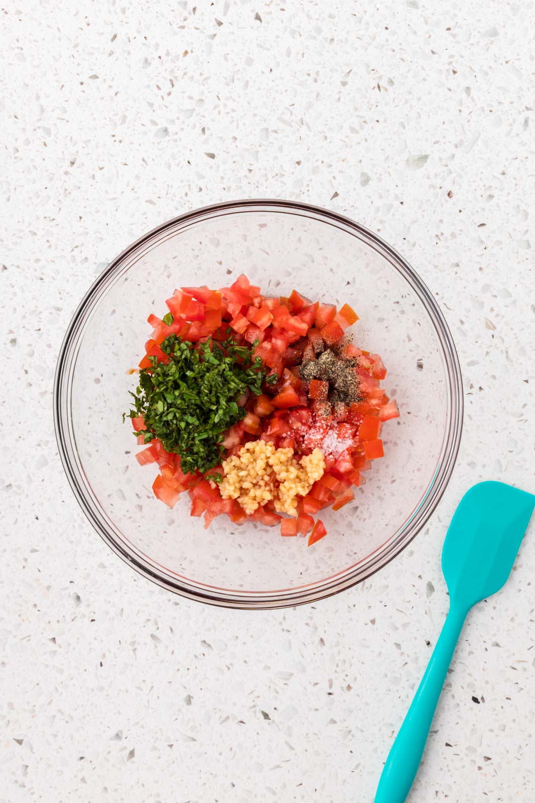 Tomatoes, garlic, basil and seasonings in a mixing bowl.