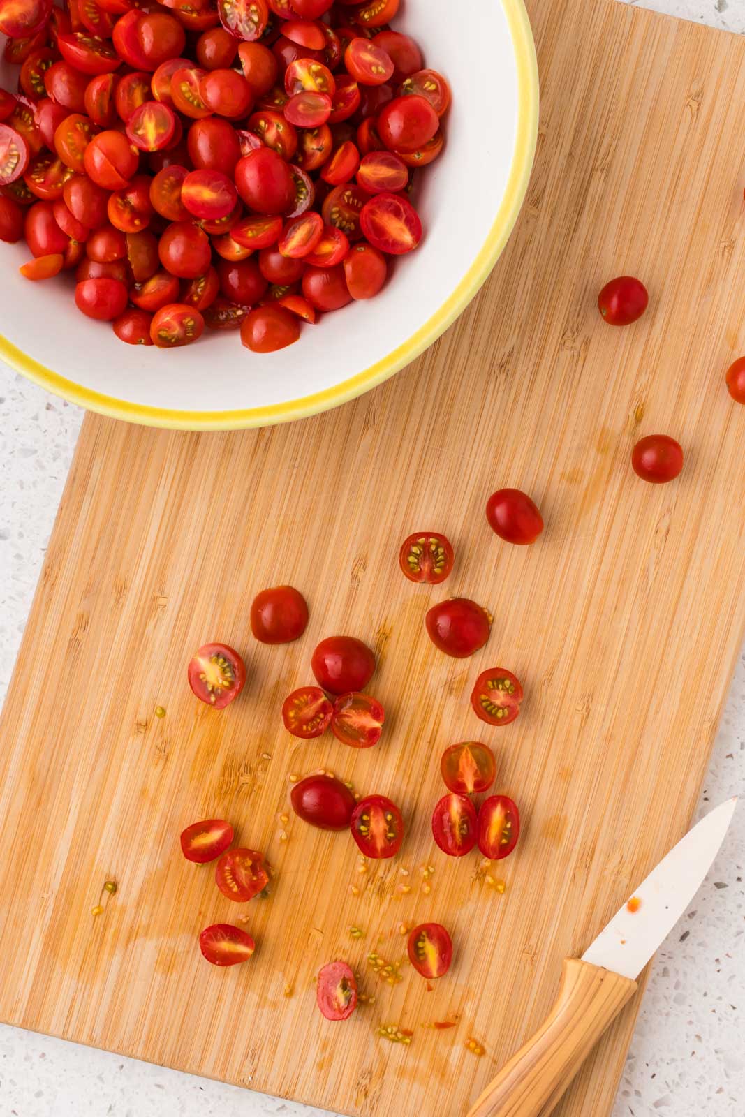 Cherry tomatoes chopped on a cutting board.