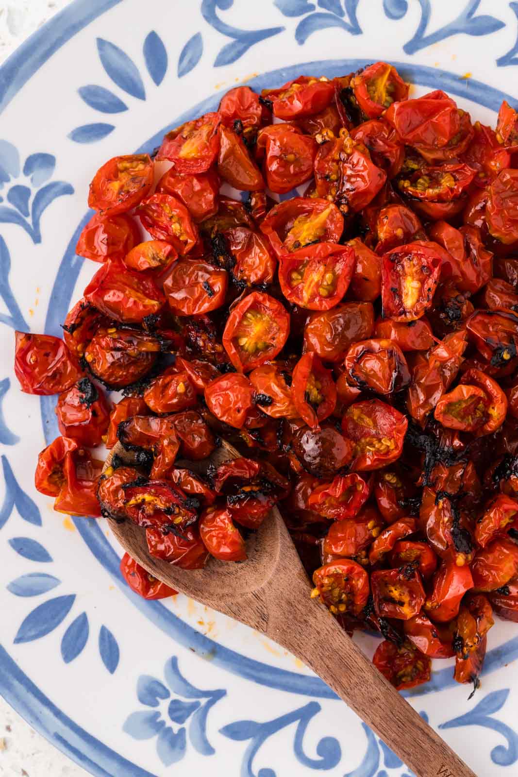 Roasted Cherry Tomatoes on a plate with a wooden spoon.
