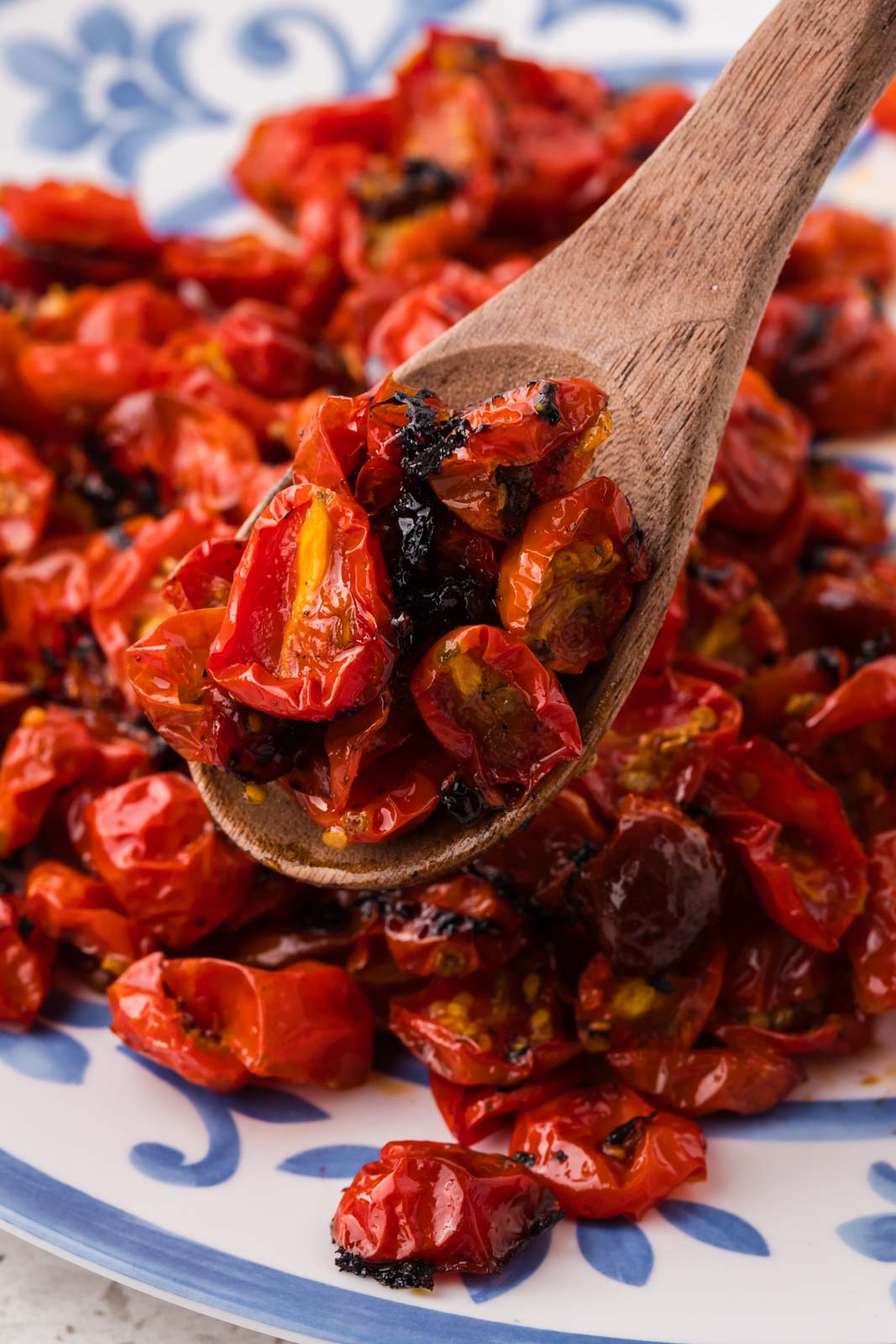 Roasted cherry tomatoes on a plate with a spoonful in the center.